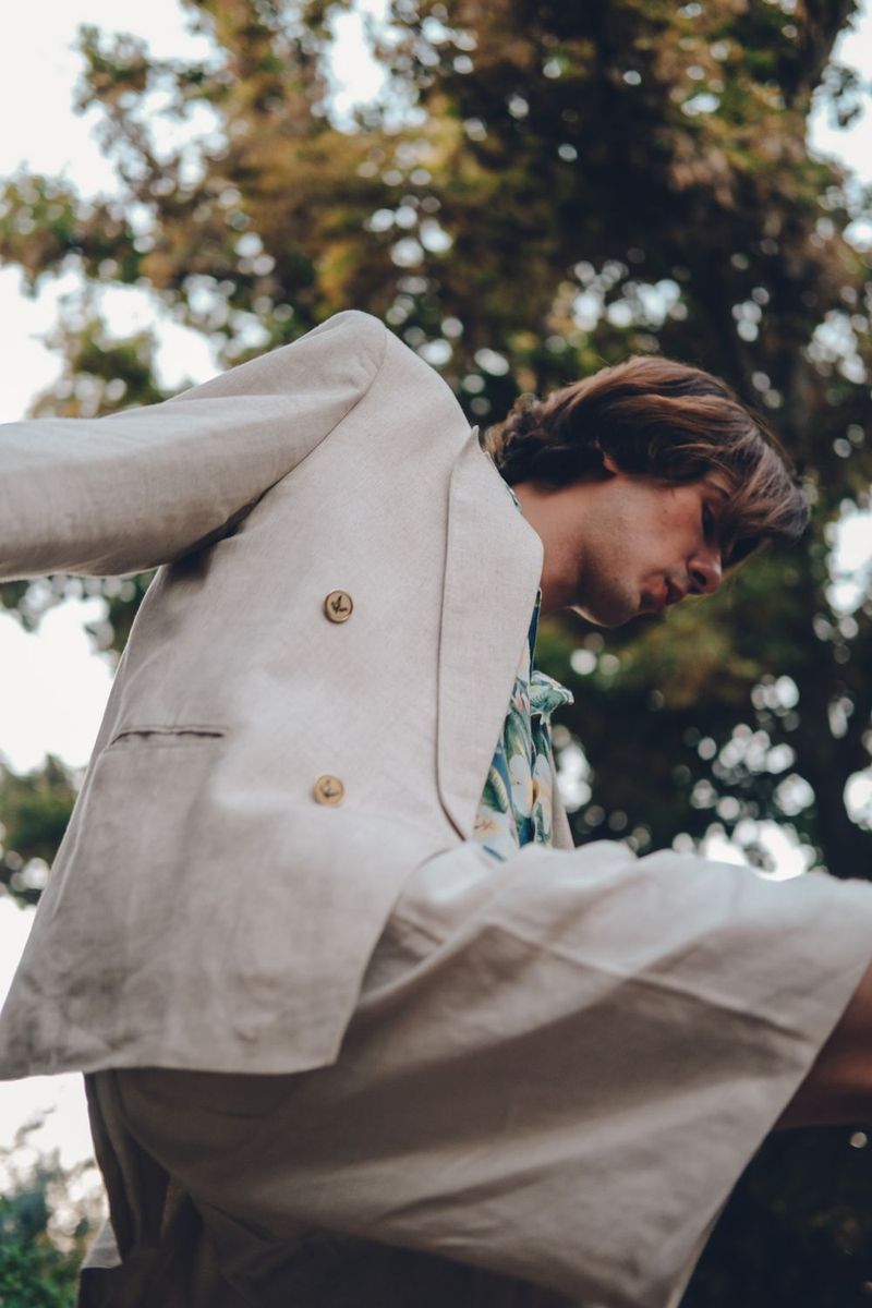 A man in a pale linen suit and floral shirt outdoors.